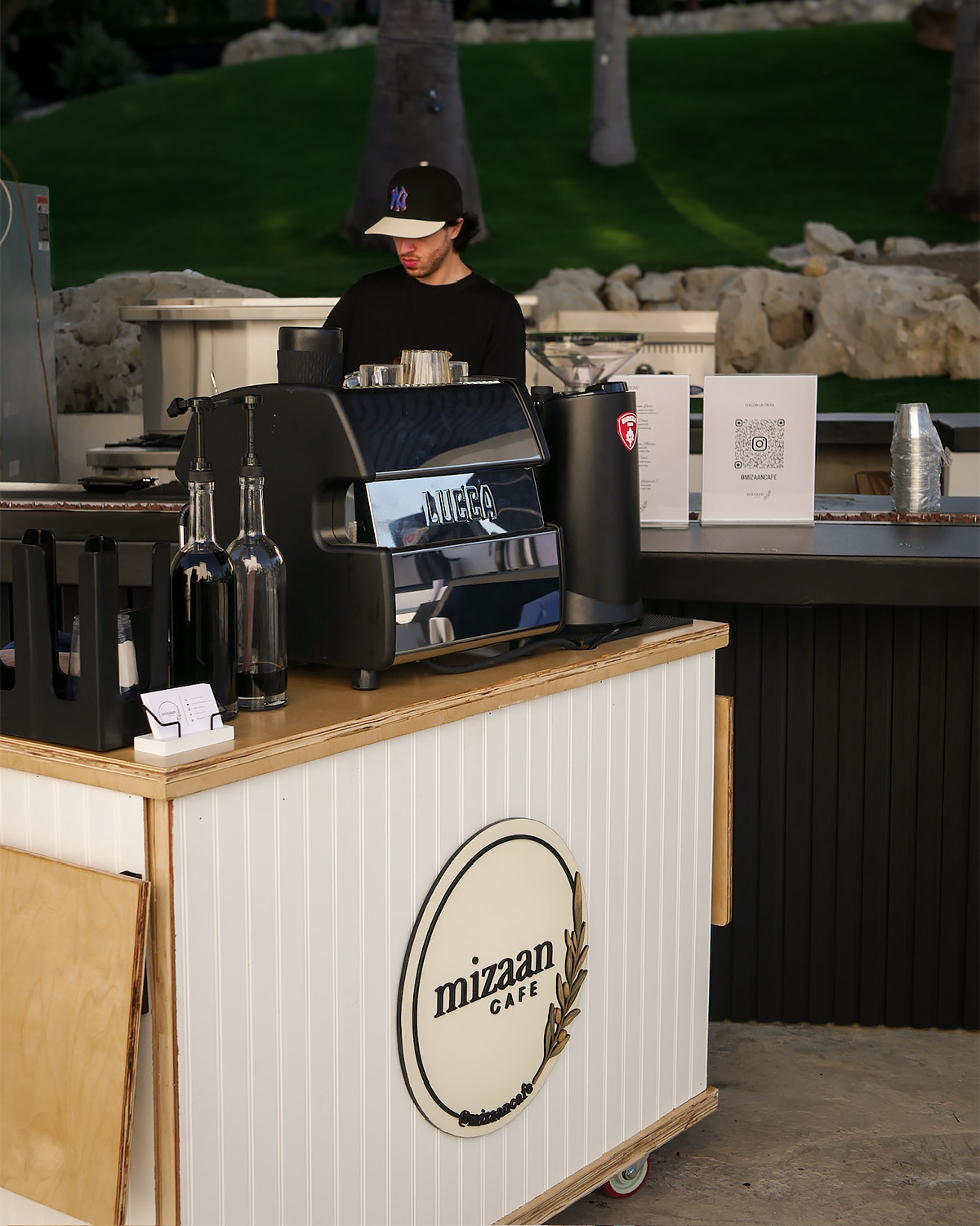 The Mizaan coffee cart set up at an outdoor event, with a barista at the espresso machine